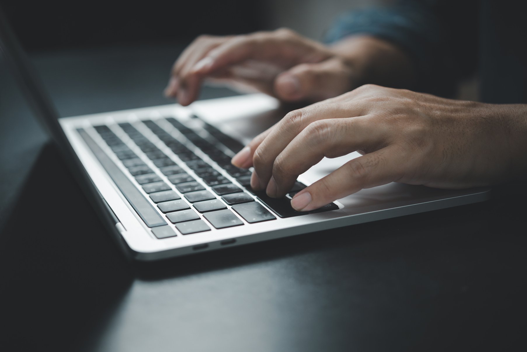 Man using computer laptop working internet searching social media and communications digital technology online at desk.